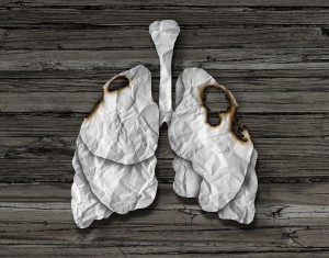 Human lung cancer concept or illness and losing human lungs health care symbol as a decline in respiratory function caused by a tumor disease as the organ made of crumpled white paper with burnt holes on a wood background.